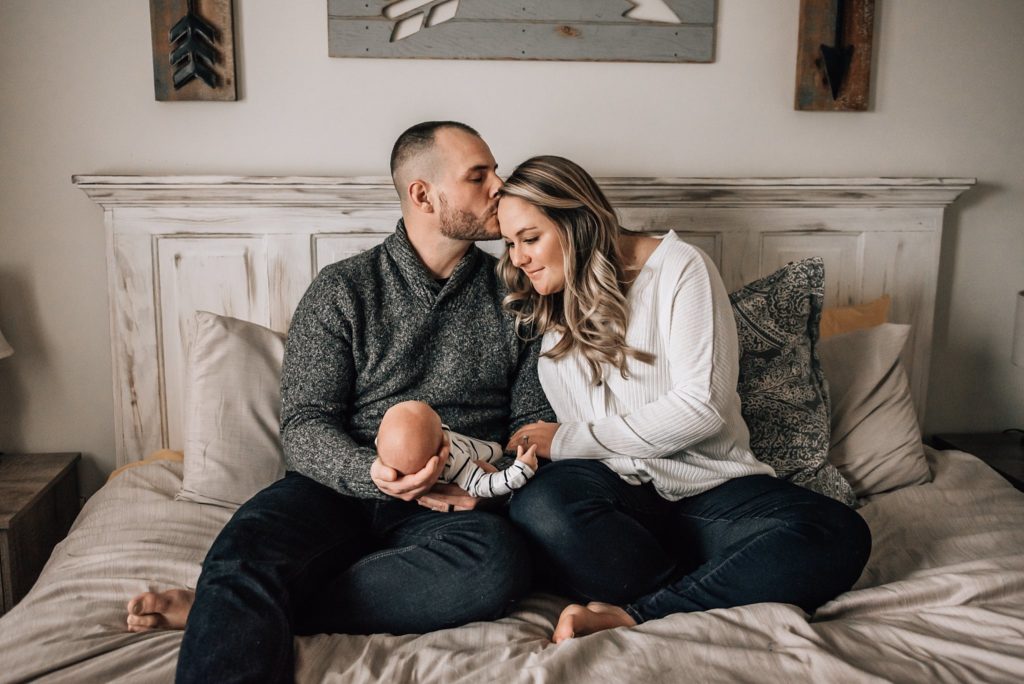 parents sitting in bed with newborn baby